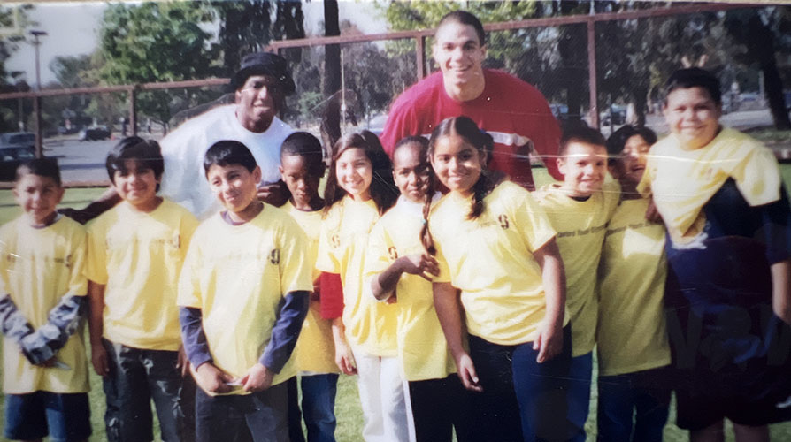 10 smiling kids in yellow t-shirts posing with two adults