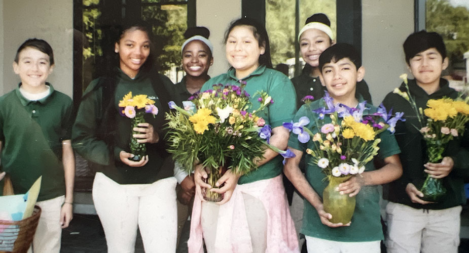 Seven middle schoolers holding flowers in vases